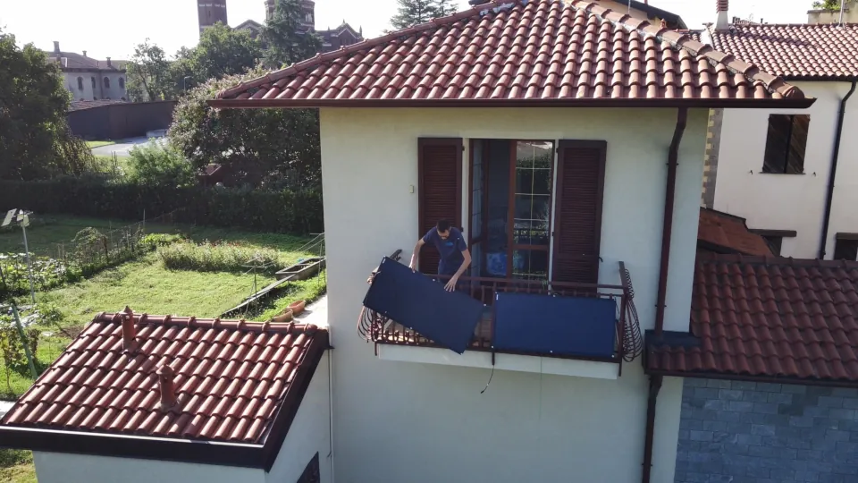 Montaggio di un pannello solare flessibile Eco-Worthy da 200W sulla ringhiera del balcone, ripreso frontalmente dalla finestra